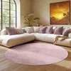 A living room scene with a sectional sofa, pillows, a plant, and a large round rug. Podgląd zdjęcia produktu