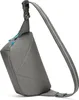 A gray sling bag with blue zipper pulls is shown against a white background. Voir les images du produit