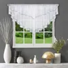 A white lace valance curtain is displayed over a window with a green garden visible outside. Decorative vases and a lamp are on a shelf below. Podgląd zdjęcia produktu