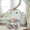 A person is holding the toy arch of a baby bouncer where a baby is sitting. Anteprima dell’immagine prodotto