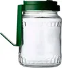 A clear studio shot of a glass jar with a green lid and handle, filled with a white substance. Náhľad obrázku produktu