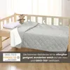 A quilted blanket is laid out on a wooden crib with a teddy bear and a pillow. Náhled obrázku produktu