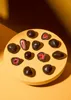 Chocolate-covered strawberries arranged on a yellow circular platform against a brown background with dramatic lighting. Produktbild-Vorschau