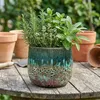 A planter with herbs on a wooden table, with other terracotta pots in the background. Produktbild-Vorschau