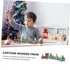 A young boy plays with a wooden train in front of a Christmas tree. Náhled obrázku produktu