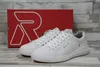 A pair of white Rieker sneakers is displayed in front of a red shoebox with a large white 'R' logo. Náhľad obrázku produktu