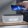 A hand is placing a smartphone on top of a digital alarm clock with a wireless charging feature. Produktbild-Vorschau
