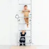 Two young children are playing on a metal climbing wall indoors. Voir les images du produit