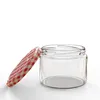 A clear studio shot of an empty glass jar with a red and white checkered lid slightly ajar. Náhled obrázku produktu