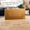 A close-up of a cardboard advent calendar box with text and graphics, placed on a wooden table. Produktbild-Vorschau