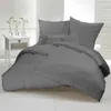 A neatly made bed with grey bedding, set against a white background with white blinds. Produktbild-Vorschau