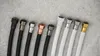 A collection of plumbing hoses with different colored fittings laid out on a textured gray surface. Anteprima dell’immagine prodotto