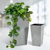 Two tall, square planters with a marble-like gray finish. One planter is larger and contains a lush green and yellow variegated plant with vines trailing down. The smaller planter is empty and sits to the right. Produktbild-Vorschau