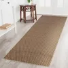 A long runner rug with a geometric pattern is laid out on a light-colored wooden floor in a hallway. A white console table with books on it is to the left, and a wooden accent table is to the right. Podgląd zdjęcia produktu