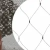 A close-up view of a net of white Christmas lights, with a blurred background of a snow-covered tree and chair. Produktbild-Vorschau