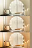 A vanity mirror with lights is displayed on a shelf with decorative bottles. Náhled obrázku produktu
