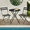 A black metal bistro set with two chairs and a round table is set up on a wooden deck next to a swimming pool. A slice of cake is on the table. Produktbild-Vorschau