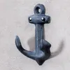 A dark gray anchor-shaped wall hook mounted on a textured light gray wall. Produktbild-Vorschau