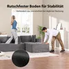 A woman wearing headphones walks on a sectional sofa while a man adjusts a part of the sofa. Produktbild-Vorschau