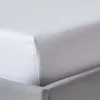 A close-up view of a white fitted sheet on a bed. Produktbild-Vorschau