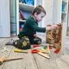 A young boy is playing with a wooden toy tool set on the floor. Anteprima dell’immagine prodotto