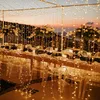 A beautifully decorated outdoor dining table set for an event, illuminated by numerous string lights. Náhľad obrázku produktu