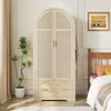 A bedroom scene featuring a large arched wardrobe with cane detailing and drawers, next to a bed. Podgląd zdjęcia produktu