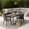 An outdoor patio scene with a sectional sofa, dining table and chairs, and a dog lying on the rug. Produktbild-Vorschau