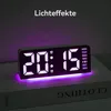 A digital alarm clock with a purple light effect is displayed on top of a book. Produktbild-Vorschau
