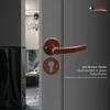 A close-up of a brown door handle and keyhole plate on a gray door, with a glimpse of an interior hallway in the background. Produktbild-Vorschau