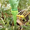 A green plastic plant watering device with a yellow valve is inserted into the soil next to green plants. Voir les images du produit