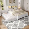 A bedroom scene featuring a white bed with a trundle bed pulled out, a rug, and a robot vacuum cleaner. Produktbild-Vorschau