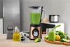 A blender with green smoothie, ingredients, and kitchen accessories on a wooden countertop. Voir les images du produit