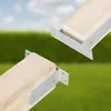 Two metal brackets attached to wooden posts, set against a blurred background of green grass and a blue sky. Anteprima dell’immagine prodotto