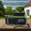 A green emergency radio with a solar panel on top, placed on a wooden table outdoors, with a house and garden in the background. Produktbild-Vorschau