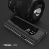 A black flip case for a smartphone is shown in front of a camera lens. Produktbild-Vorschau