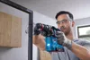 A man is using a cordless hammer drill to drill into a metal frame. Produktbild-Vorschau