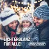 A family is smiling and bundled up in winter clothing, with blurred Christmas lights in the background. Anteprima dell’immagine prodotto