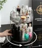 A rotating cosmetic organizer filled with various beauty products is shown on a black surface, with a hand reaching to turn it. Anteprima dell’immagine prodotto