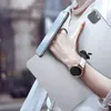 A person holding a laptop and a smartphone, with a smartwatch on their wrist. Náhled obrázku produktu