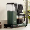 A green Moccacoffee maker sits on a kitchen counter next to a jar of coffee beans. Náhled obrázku produktu