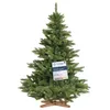 A green artificial Christmas tree with a wooden stand, featuring a tag with product information. Produktbild-Vorschau