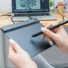 A person's hands are using a drawing tablet connected to a laptop, with art supplies in the background. Náhľad obrázku produktu