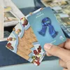 A hand is holding a card with a blue scarf on it, with other cards and game elements visible in the background. Produktbild-Vorschau