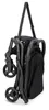 A folded black stroller is hanging by a strap against a white background. Voir les images du produit