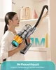 A woman is using a cordless vacuum cleaner to clean a shelf. Produktbild-Vorschau