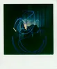 A person is captured mid-air, surrounded by blue light trails, against a dark, curtained background. Voir les images du produit