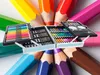 A set of art supplies in a case, surrounded by colored pencils. Podgląd zdjęcia produktu