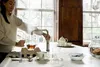 A woman is filling a teapot with hot water from a Quooker tap in a kitchen. Anteprima dell’immagine prodotto