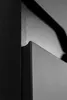 A close-up, abstract view of the corner of a black cabinet or furniture piece, highlighting its textured surface and clean lines. Voir les images du produit